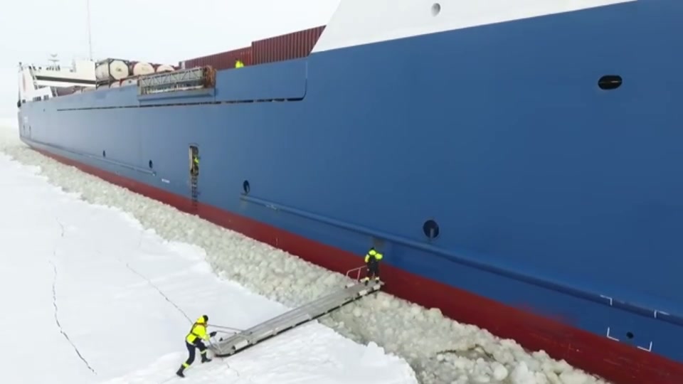 Pilot steps onto moving container ship in icy port